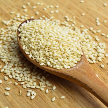 Organik taze susam tohumları, bambu kesme tahtasındaki tahta kaşıkta.