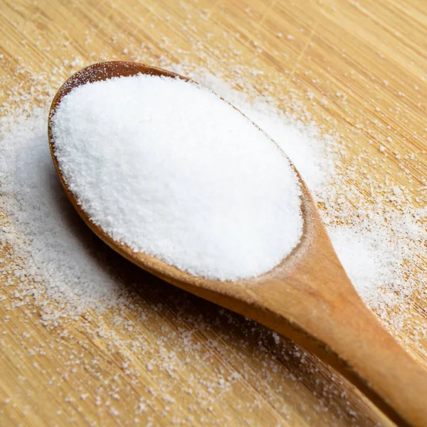 Bambu kesme tahtasında ahşap kaşıkta yemek pişirmede kullanılan masa tuzu.