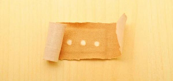 Beige cloth band aid plaster on a wooden background