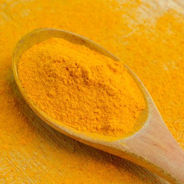 Bambu ahşap arka planda ahşap kaşıkta taze zerdeçal tozu.