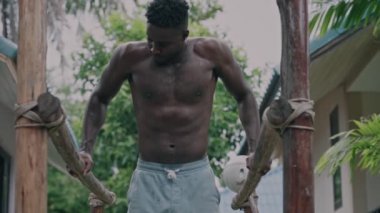 Genç Afro-Amerikan zinde adam paralel barlarda yüzüyor.