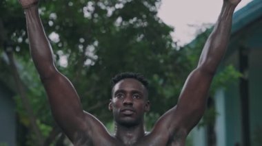 Genç Afro-Amerikan formda adam barfiks çekiyor.
