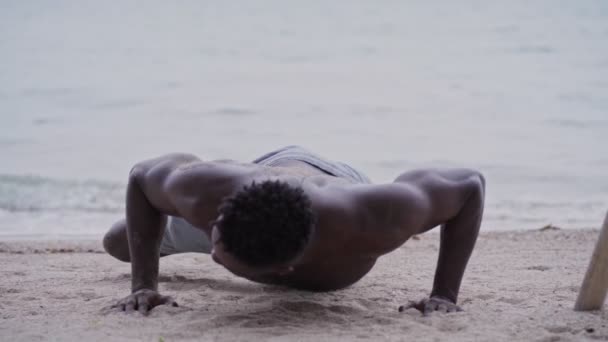 Afro-américain faire des pompes tout en faisant de l'exercice à la plage — Video