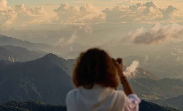 Ung kvinna fotograf tar foto på bergstopp — Stockfoto