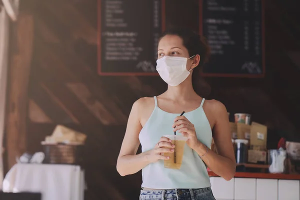 Vrouw met beschermend masker koopt eten en drinken in café om mee te nemen — Stockfoto