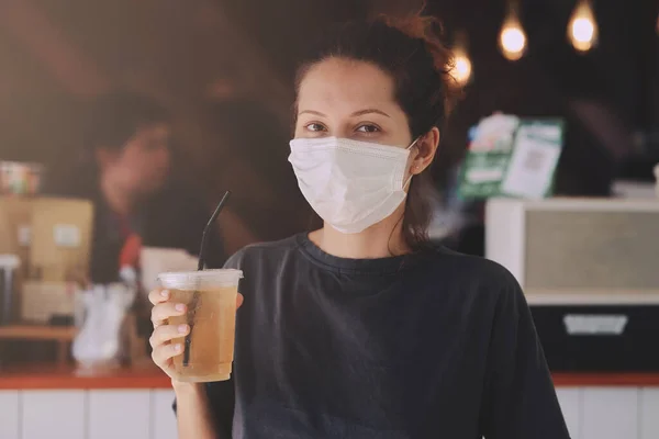 Vrouw met beschermend masker koopt eten en drinken in café om mee te nemen — Stockfoto