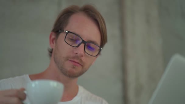 Porträtt av en man utvecklare bär glasögon arbetar med bärbar dator på kafé — Stockvideo
