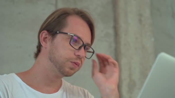 Porträtt av en man utvecklare bär glasögon arbetar med bärbar dator på kafé — Stockvideo
