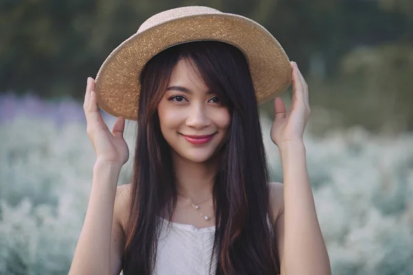 Beautiful Asian woman wear white dress and straw hat walking in white cutter flowers garden