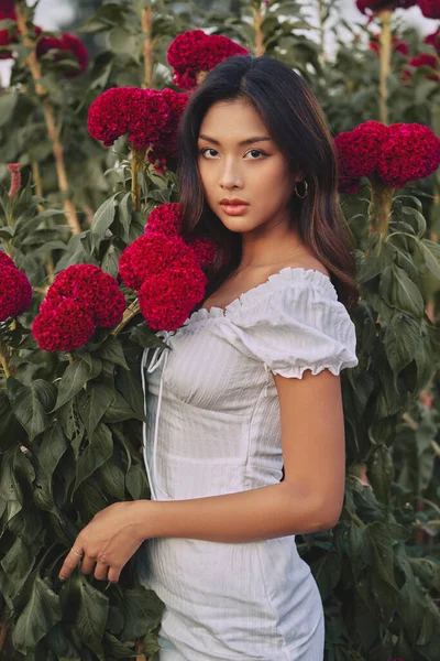 Mode porträtt av en vacker ung thailändsk kvinna omgiven av blommor. Vårblomning — Stockfoto