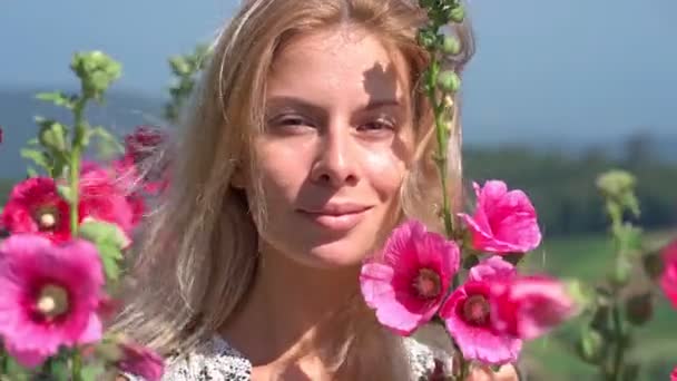 Blond kijken recht in de camera op het bloemenveld — Stockvideo