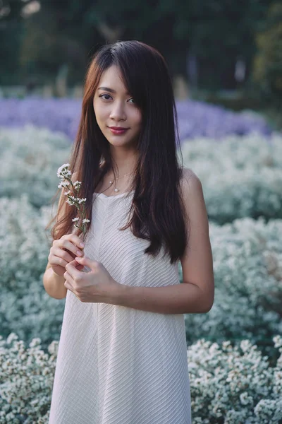 Vacker asiatisk kvinna bär vit klänning promenader i vit cutter blommor trädgård — Stockfoto