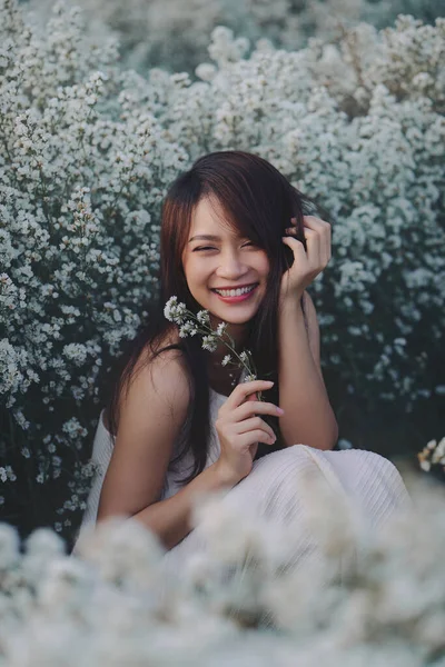 Vacker asiatisk kvinna bära vit klänning sitter i trädgården av vita blommor — Stockfoto