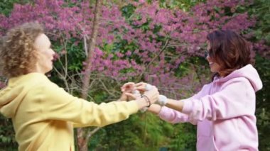 Homoseksüel lezbiyen çift sakura bahçesinde sarılıyor. İki kadın el ele tutuşurken sevgi ve desteği paylaşır. Gay Ailesi. LGBT arkadaşlık kavramı