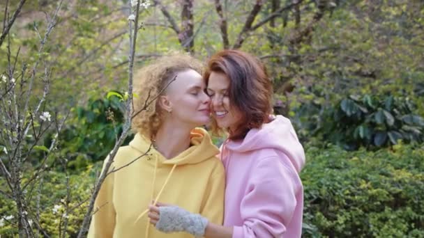 Coppia lesbica che abbraccia in un giardino di sakura. Due donne condividono amore e sostegno mentre si tengono per mano. Famiglia gay. Concetto LGBT di amicizia — Video Stock