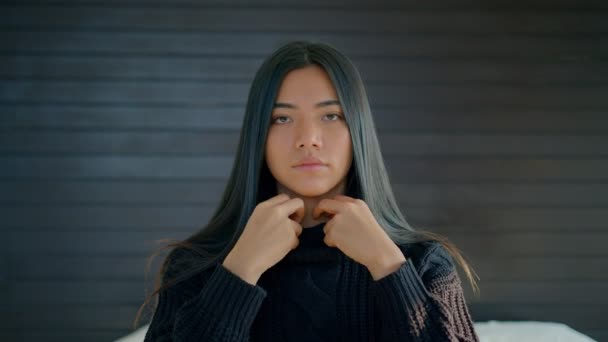 Beautiful brunette woman with beautiful long hair pulls a black sweater over her face on a bed and looking straight at the camera in slow motion — Stock Video