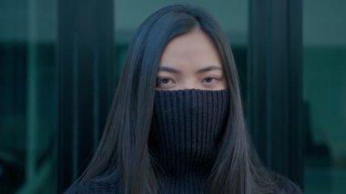 Güzel, uzun saçlı esmer bir kadın yüzüne siyah bir kazak geçirir ve yavaş çekimde kameraya bakar.