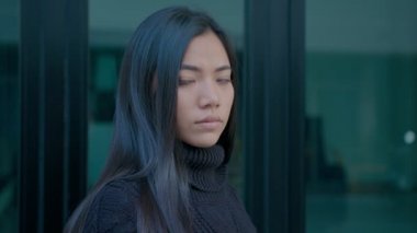 Siyah kazaklı, uzun saçlı güzel esmer kadın doğrudan kameraya bakıyor.