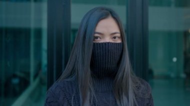 Güzel, uzun saçlı esmer bir kadın yüzüne siyah bir kazak geçirir ve yavaş çekimde kameraya bakar.