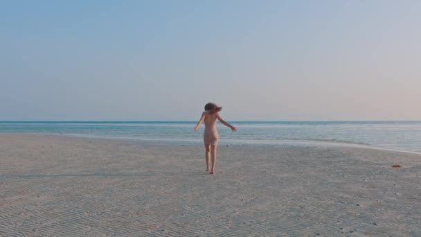 Brun hårig vacker kvinna i rosa klänning lyssna musik på sandstrand i slow motion på solnedgången — Stockvideo