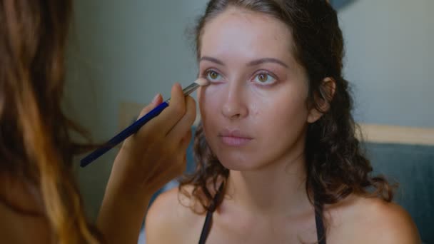 Un artista de maquillaje hace un maquillaje brillante para una hermosa modelo de chica — Vídeo de stock