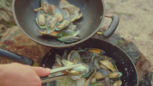 シェフはビーチの火の上に鍋で新鮮なムール貝を調理します。スローモーションフードビデオ。ムール貝とイタリアのパスタを調理するプロセス — ストック動画