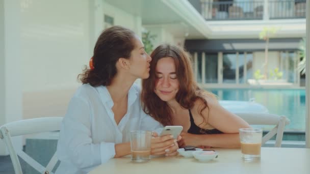 Pareja femenina feliz usando un teléfono inteligente mientras bebe café — Vídeo de stock