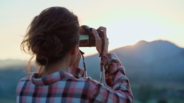 Фотограф, фотографує гірський пейзаж на заході сонця — стокове відео