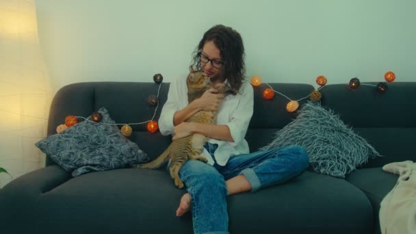 Женщина отдыхает на диване с котом — стоковое видео