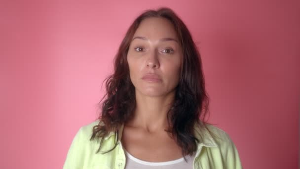 Porträt einer nachdenkenden jungen Frau, die im Moment der Idee mit dem Finger auf rosa Studiohintergrund zeigt. Lächelndes glückliches Mädchen zeigt Eureka-Geste — Stockvideo