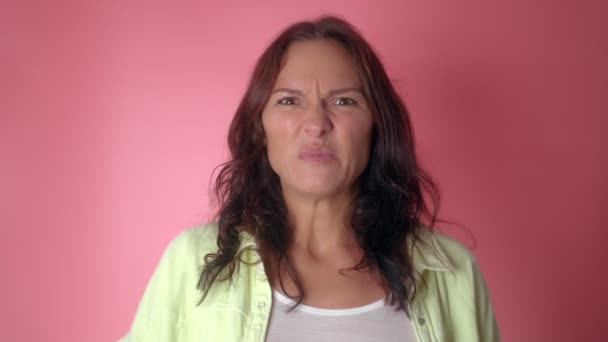 Close up of a young girl under stress blowing smoke from her nose, isolated on a pink background — Stock Video