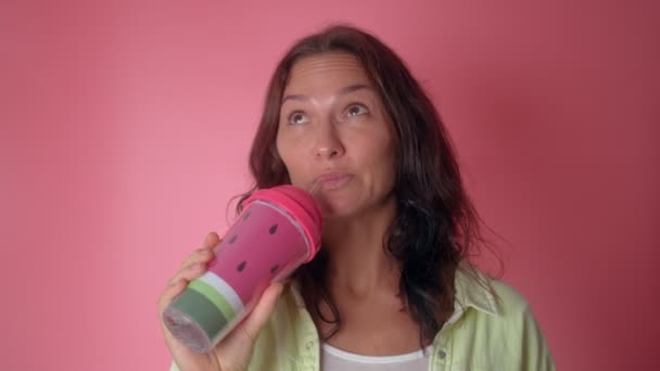 Young woman show reusable mug in her hand on a pink background. Use reusable mug and straw for replacement plastic cup can save the earth. Reduce ocean pollution — Stock Video