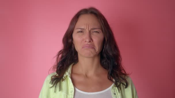 Joven chica atractiva llorando desesperadamente sobre un fondo de pared rosa — Vídeos de Stock