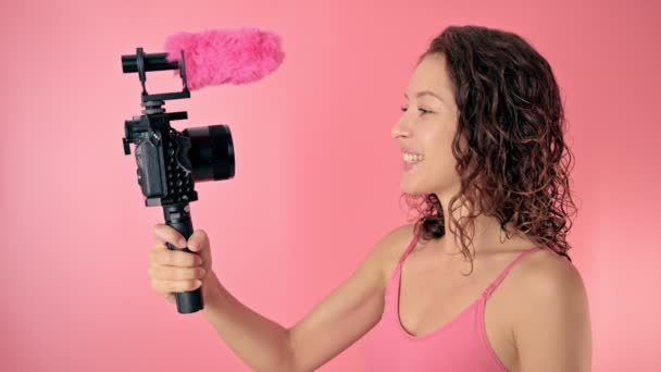 Mulher jovem vlogger gravação transmissão em câmera lenta em um fundo rosa — Vídeo de Stock