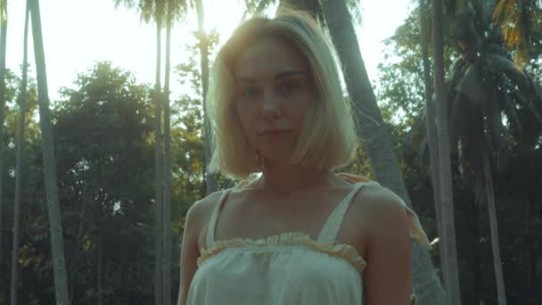 Joven rubia de pie contemplando la selva tropical, la luz del atardecer que viene de arriba. vídeo en cámara lenta — Vídeos de Stock