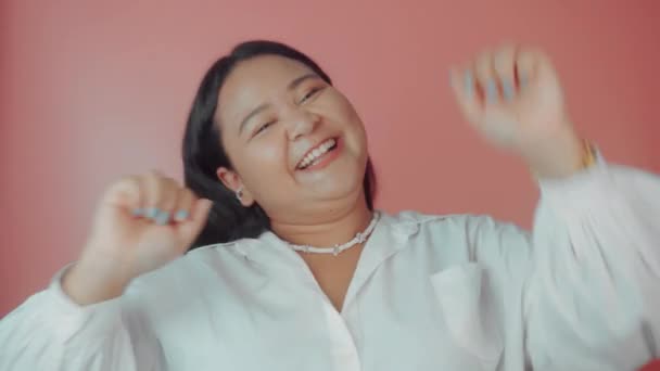 Beyaz gömlekli Asyalı kadın pembe arka planda yalnız poz veriyor. Vücut pozitif konsept — Stok video