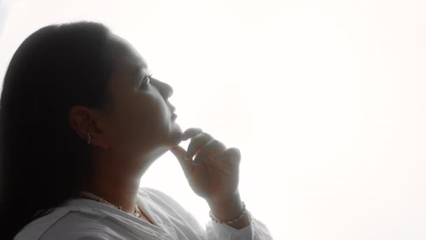 Silhouette di una donna in camicia bianca premurosa con mano vicino al mento pensando di risolvere un problema — Video Stock
