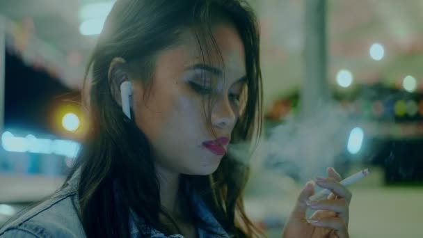 Девушка курит перед ржавой классической машиной, печатая сообщение поздно ночью — стоковое видео
