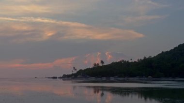 Adalar sahilde gün batımını izliyor.