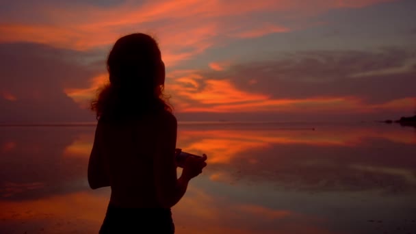 Touristin fotografiert mit Handykamera atemberaubenden Sonnenuntergang am Strand — Stockvideo