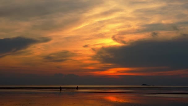 Asiatiska fiskare går på stranden vid lågvatten, silhuett av två personer vid solnedgången — Stockvideo