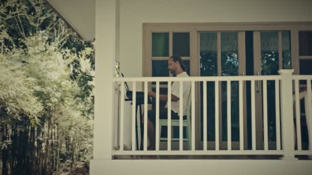 Un hombre con dos manos toca música en un instrumento de teclado. El músico se inspira en la terraza de la casa. — Vídeos de Stock