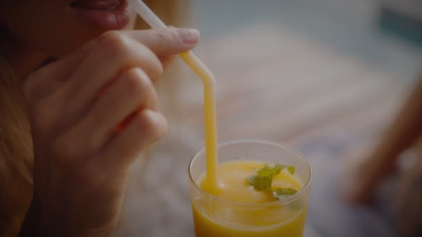 Blondýnka pije mango koktejl, zatímco se válí na slunci u bazénu na dovolené. Elegantní mladá žena pije koktejl u bazénu ve zpomaleném filmu. — Stock video