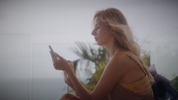 Sarışın bir kadın tatilde havuz kenarında güneşlenirken cep telefonunu kullanıyor. — Stok video