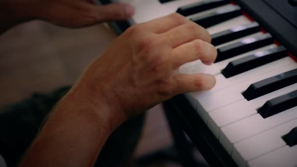 Un homme joue de la musique sur un instrument à clavier. Le musicien s'inspire de la terrasse de la maison — Video