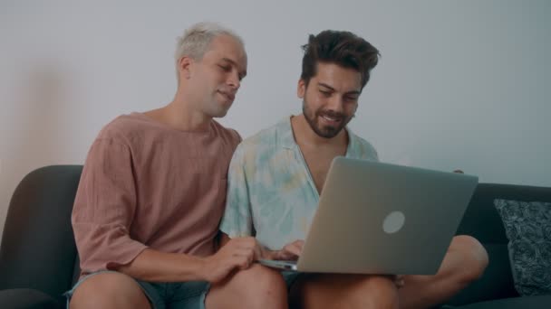Avrupalı bir eşcinsel çift evde vakit geçiriyor. Kanepeye uzanıp laptoplarını kullanıyorlar. — Stok video