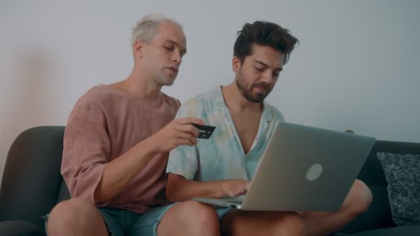 Pareja gay de compras en línea usando portátil y tarjeta de crédito — Vídeo de stock