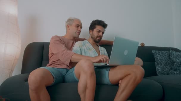 一对欧洲同性恋夫妇在家里呆了一段时间。他们躺在沙发上，用笔记本电脑 — 图库视频影像