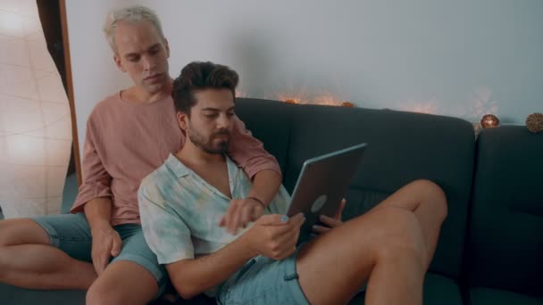 Eşcinsel çift evde vakit geçiriyor. Kanepeye uzanıp laptoplarını kullanıyorlar.. — Stok video