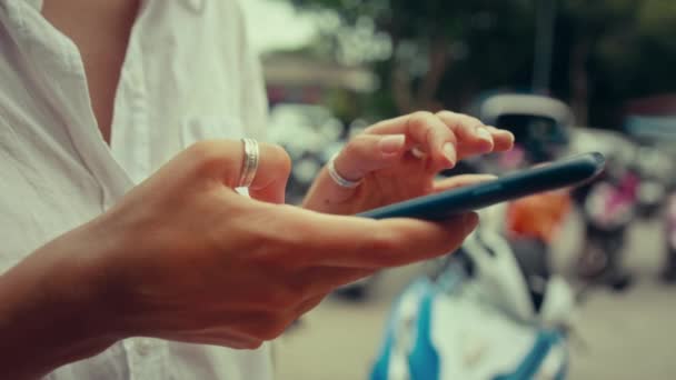 A young woman typing on a smartphone in the street — Stock Video